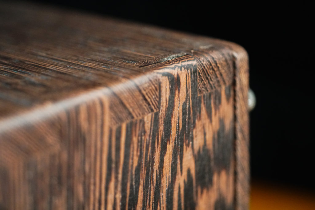 This is a close shot of Millettia Laurentii and the joint design of the resonance box. Millettia Laurentii (its Chinese name translated means “Chicken wing wood”) has deep black feather-like wood grain. It has a prominent fibrous texture and occasional small pieces of wood may chip off at the edges.