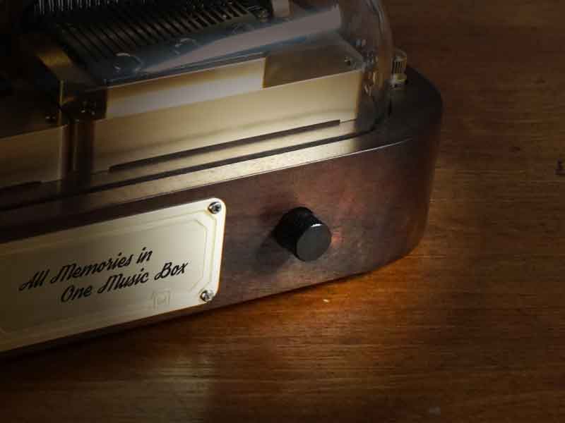 Close-up of the front metal nameplate and the song-selection knob on the N40 Sublime programmable music box.