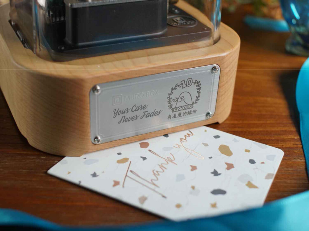Muro Box-N20智慧音乐盒，客制化雷雕『Your Care Never Fades』与『有温度的缘份』字样以及绿绣眼图案的金属铭版