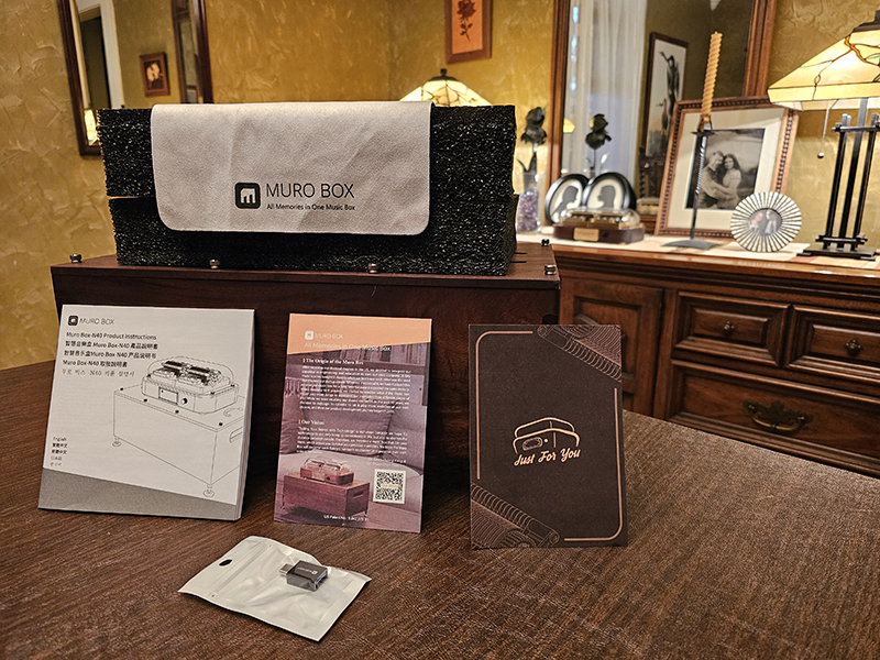Muro Box‑N40 穆风版音乐盒与其配件的开箱展示，整齐陈列于桌面上，包括产品说明书、USB‑C 转接头、Muro Box 品牌故事卡、印有「Just For You」字样的手写黑卡、N40 共鸣箱、Muro Box‑N40 穆风版音乐盒本体，以及用于擦拭上盖的柔软布料。