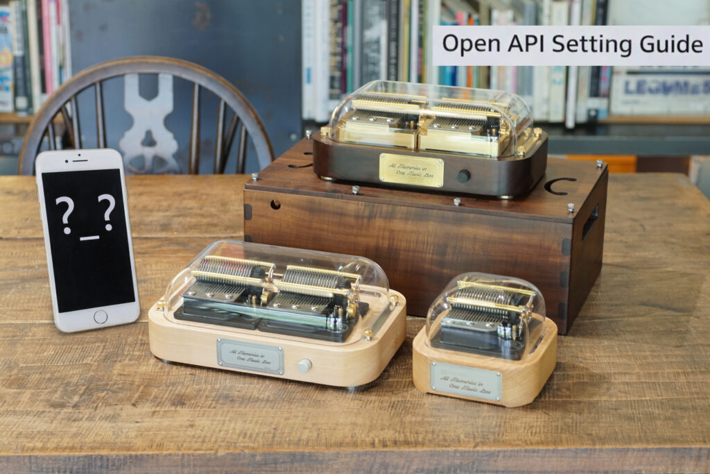 Three mechanical music boxes with transparent covers reveal their gears and combs, engraved with 'All Memories in One Music Box'. A warm wooden table and bookshelf background highlight craftsmanship and emotional design.