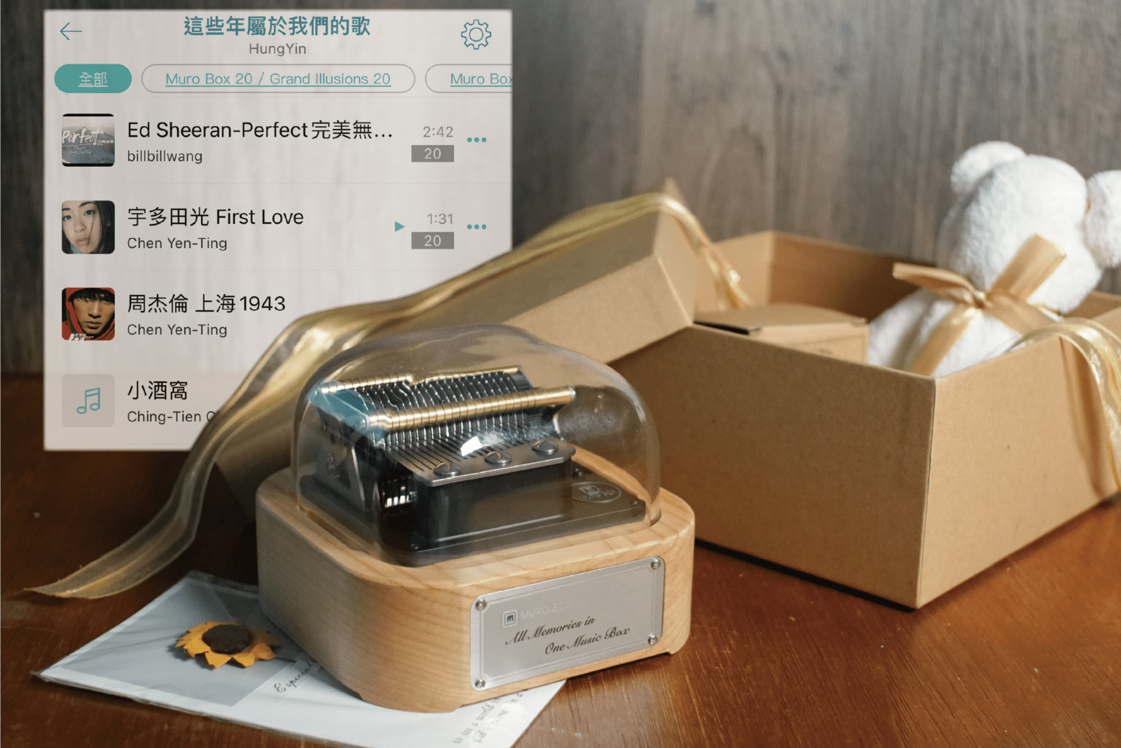 智慧音樂盒Muro Box-N20 標準版在前景，背後的APP歌單畫面是一位中文客戶在Muro Box App 內公開分享的歌單內容所做的示意圖。